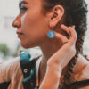 a woman with braided hair holding a persian turquoise drop earrings